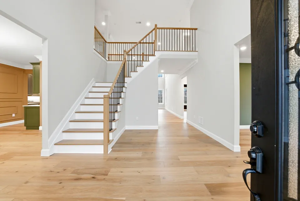 Two-story foyer with an oak and black iron staircase and wide-plank oak floors