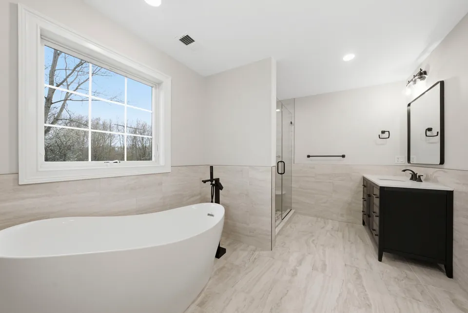 Primary bathroom with a freestanding tub, glass shower and black vanity
