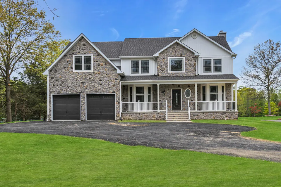 Two-story home with a fieldstone front, covered front porch and two-car garage