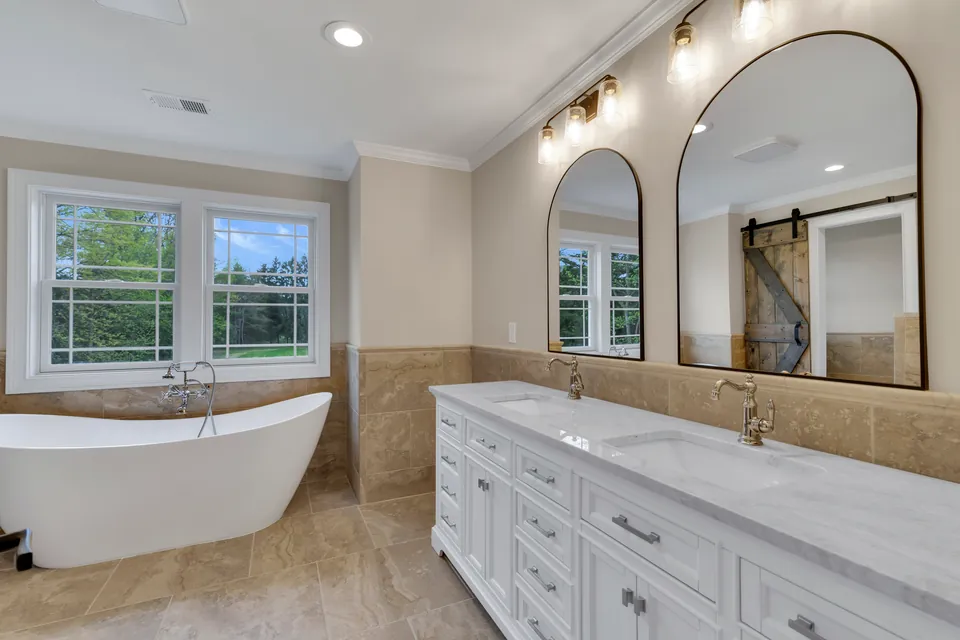 Primary bathroom with a freestanding tub, a double vanity and arched mirrors