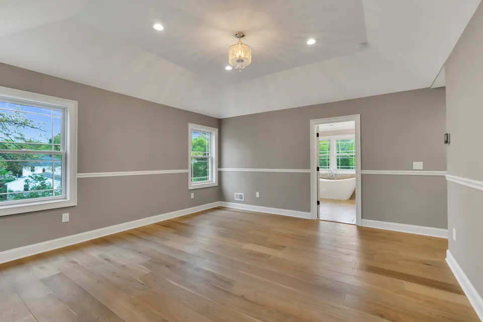 Primary bedroom with a tray ceiling, chair rail and hardwood floors