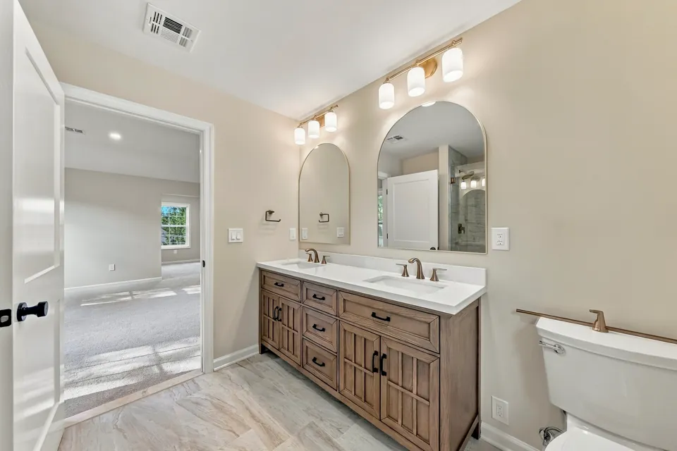 Bathroom with a wood double vanity and arched brass mirrors